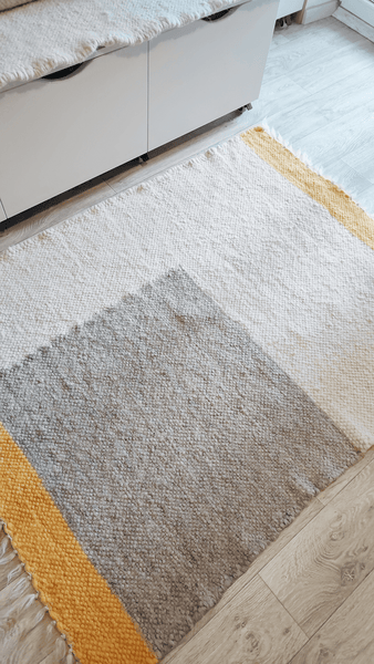 Handmade wool rug in ivory white, grey, and vibrant orange geometric pattern