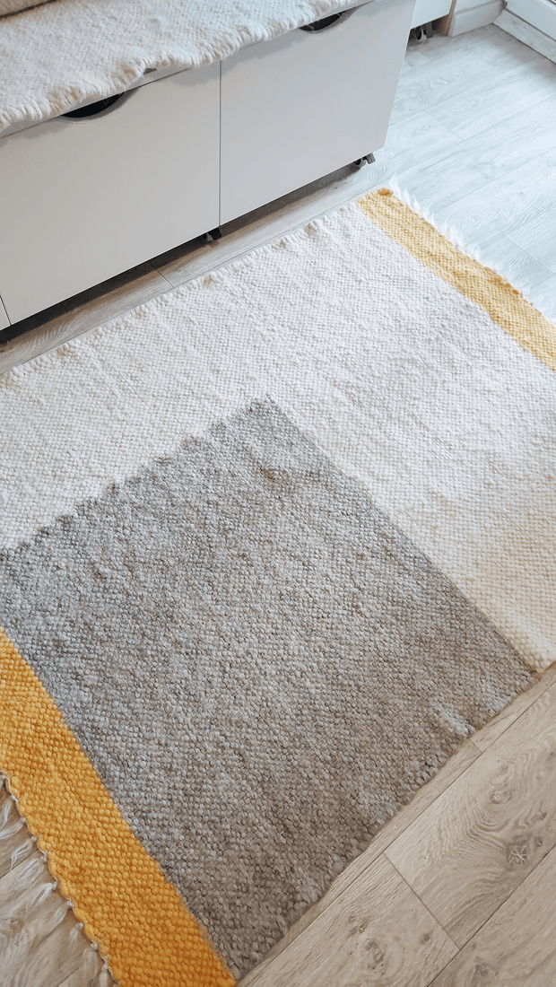 Custom size handmade wool rug in ivory, grey, and orange in a minimalist living room.