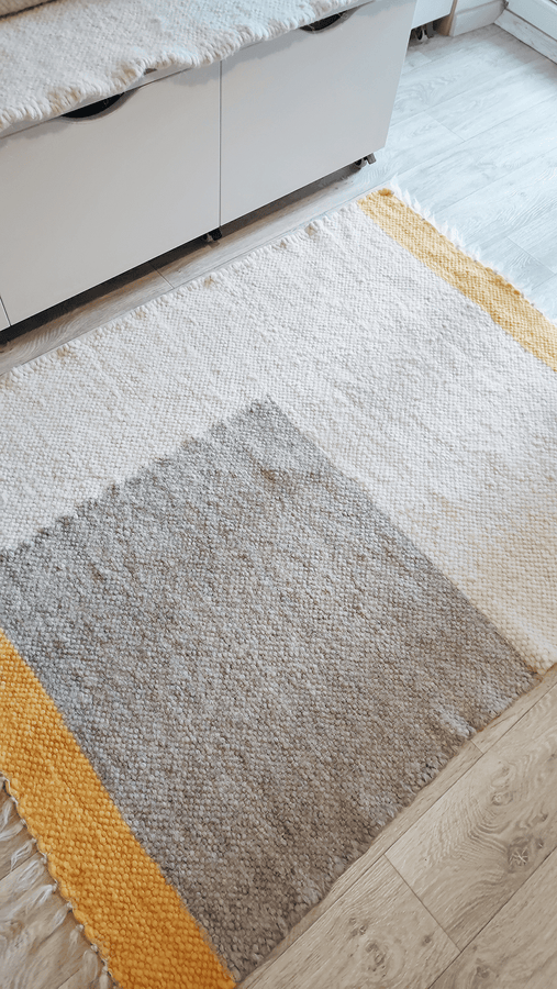 Custom size handmade wool rug in ivory, grey, and orange in a minimalist living room.