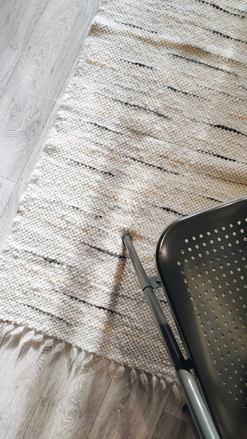 Beshka rug — modern minimalist wool rug, ivory white with orange and gray accents, sustainable handmade craftsmanship