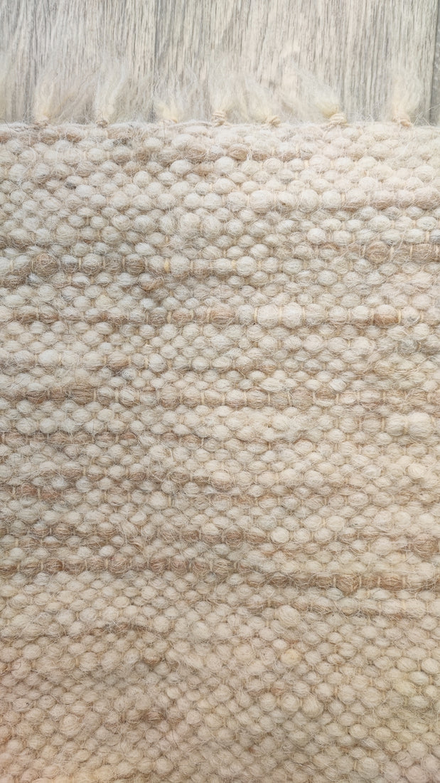 Hand-knotted undyed wool rug, beige base with ivory stripe accents, refined natural home decor. close up