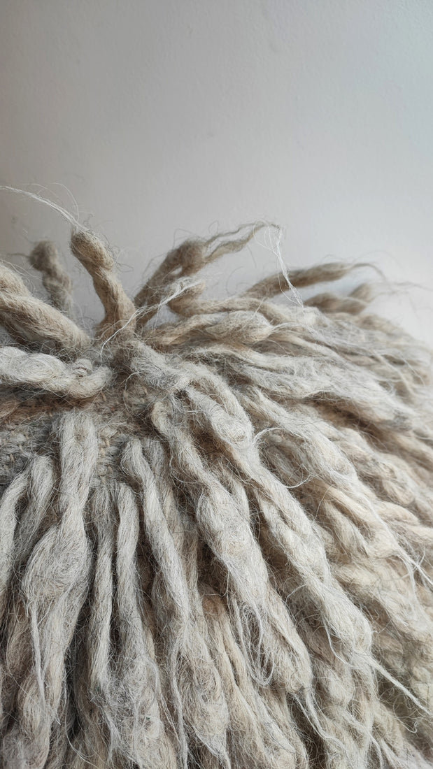 Close-up of the soft, long natural wool strands on a grey flokati pillow