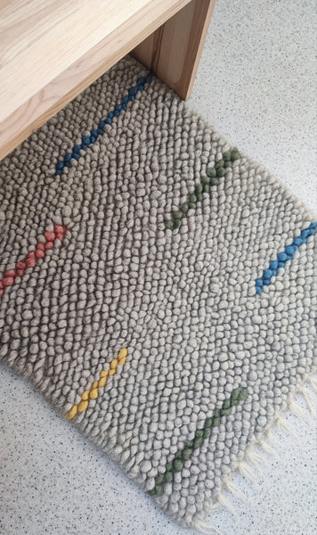 Child playing on the soft woolen Buzhok gray rainbow rug