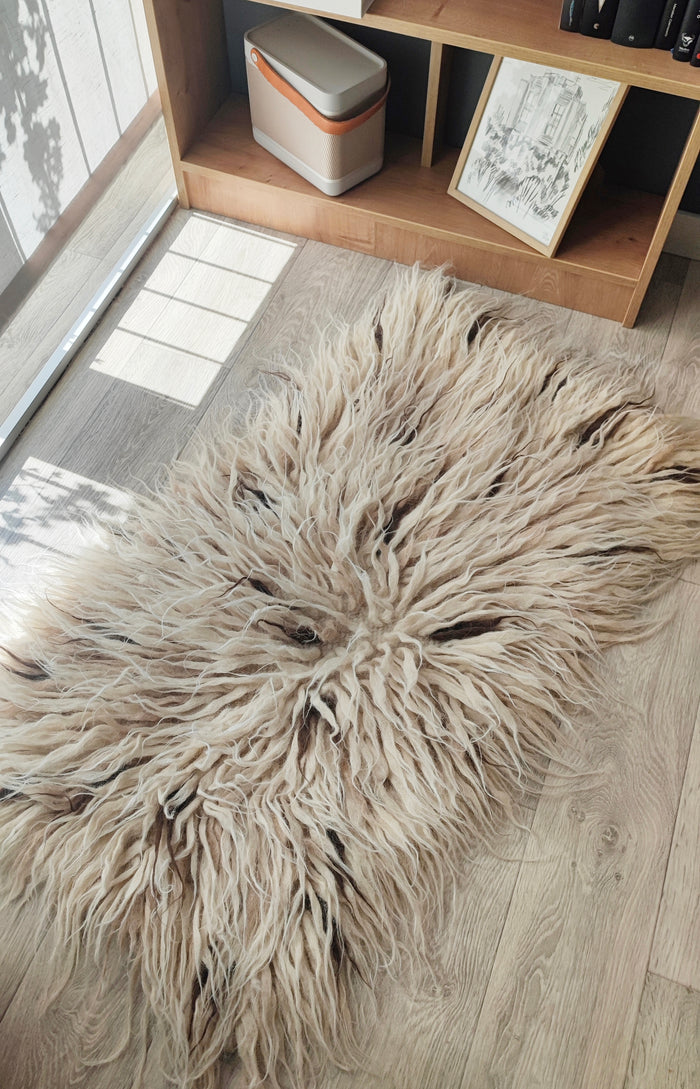 Plush wool flokati rug, ivory white tufts interspersed with subtle beige and brown strands, a tactile organic design