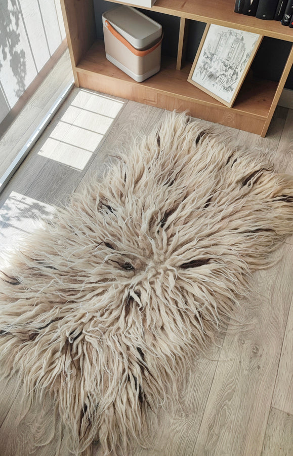 Plush wool flokati rug, ivory white tufts interspersed with subtle beige and brown strands, a tactile organic design