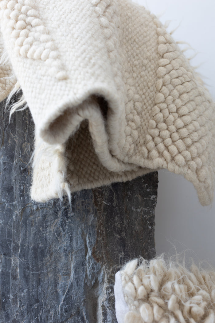 Hand-knotted ivory wool rug with organic abstract bobble motif, evoking the silhouette of distant mountain ridges
