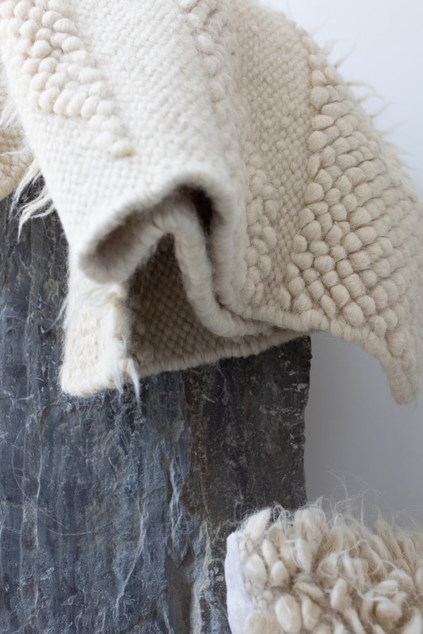 Hand-knotted ivory wool rug with organic abstract bobble motif, evoking the silhouette of distant mountain ridges