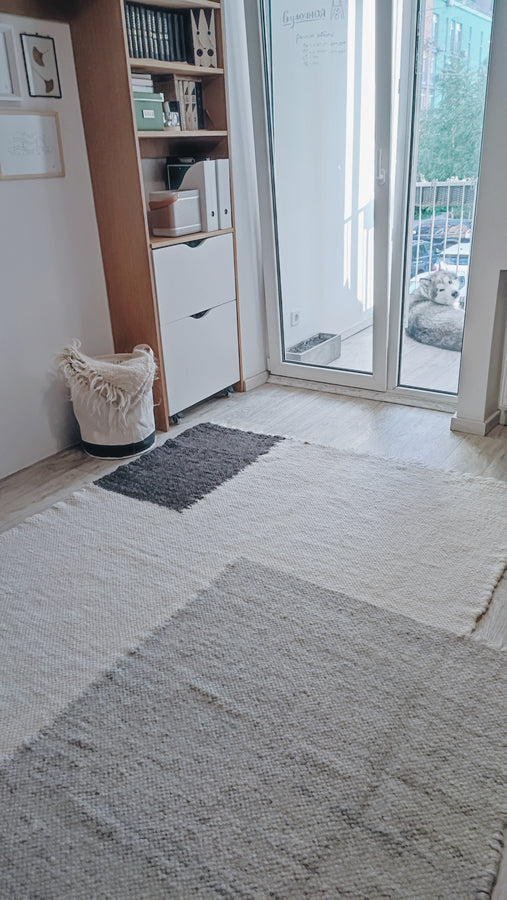 Handwoven wool rug with bold geometric squares in two shades of gray on an ivory white base, an artisan statement piece