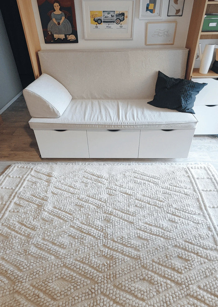 Three-dimensional ivory wool rug, double diamond pattern with tactile bobble texture, an artisan-made design icon