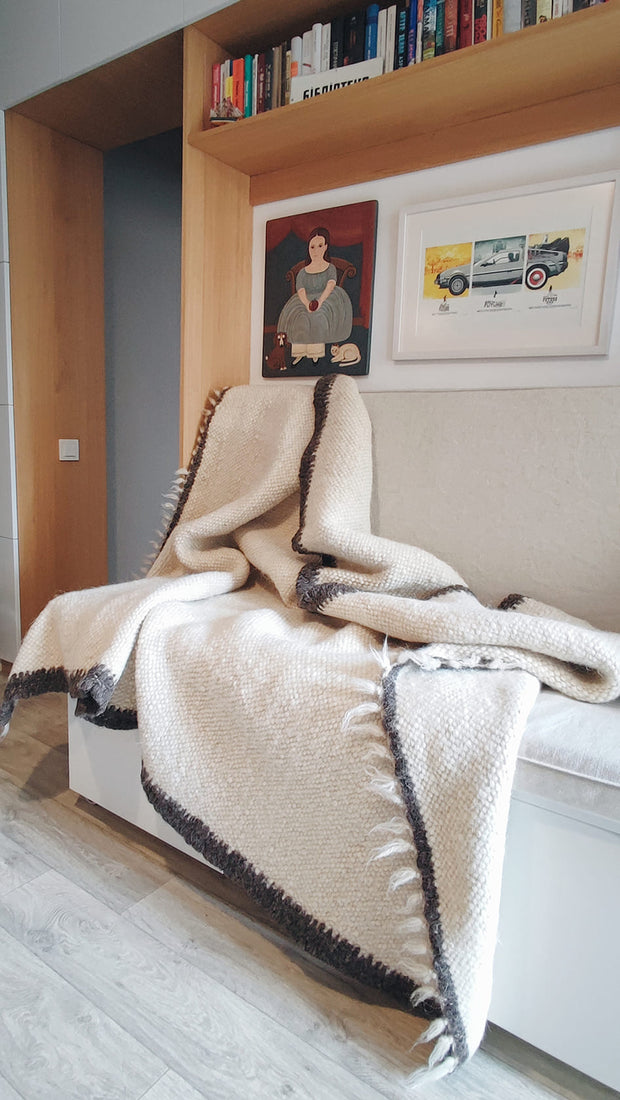 Contemporary minimalist wool blanket, ivory white with black border detail, handcrafted from natural undyed sheep wool