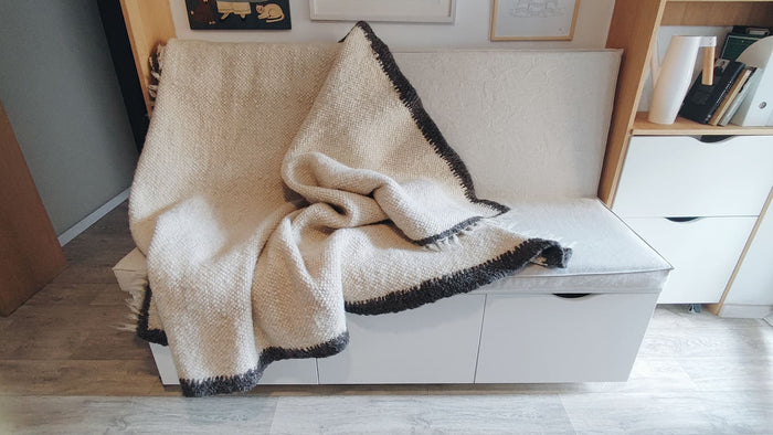 Lanna rug — modern minimalist wool rug, ivory white field with bold black border accent, sustainable handmade craftsmanship