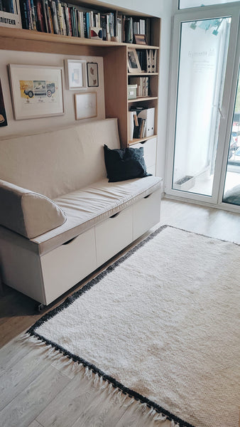 Handmade wool rug in ivory white with black border trim, minimalist Scandinavian-style design