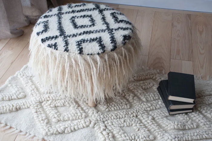 Mapico pouf with ethnic black-and-white pattern displayed on a natural wool rug