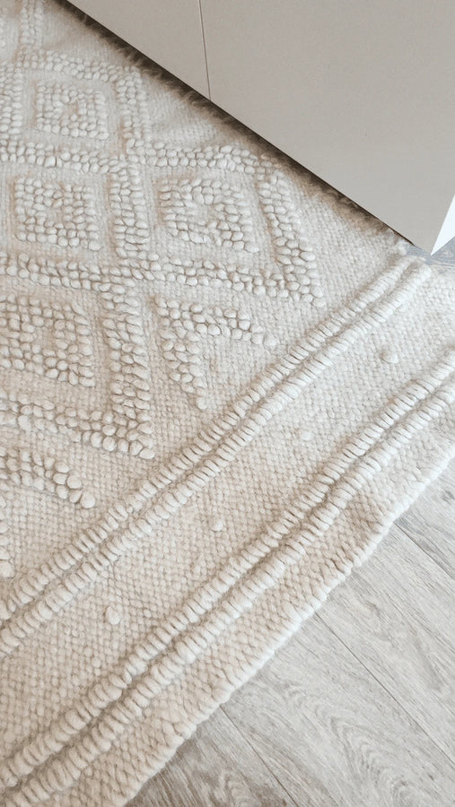 Tone-on-tone ivory wool rug featuring nested diamond pattern, hand-knotted using traditional bobble-weave (gulky) technique