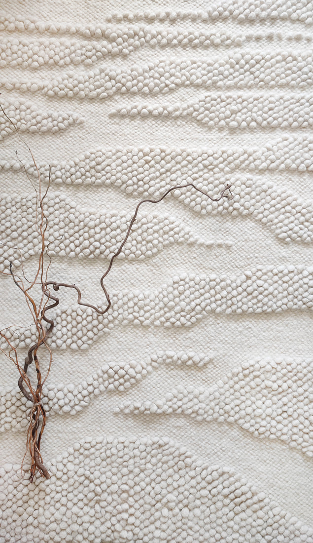 Milova rug – handwoven milky white wool rug with raised bobble texture resembling a winding river across a plain