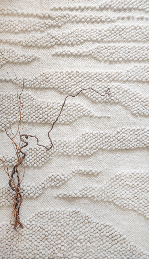 Milova rug – handwoven milky white wool rug with raised bobble texture resembling a winding river across a plain