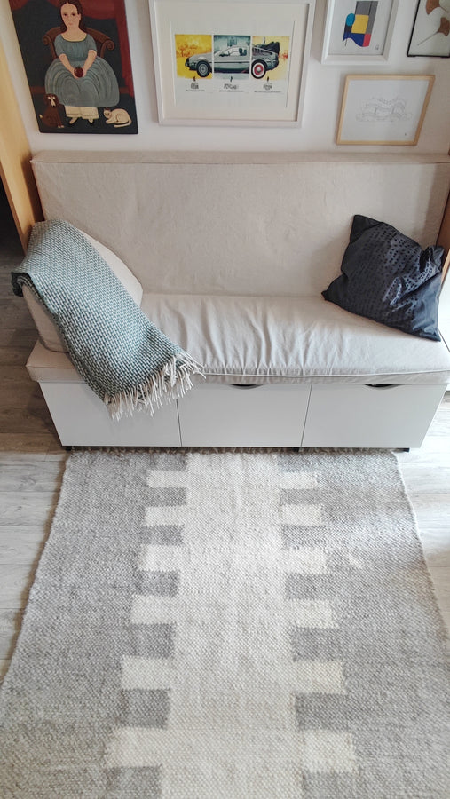 Natural undyed wool rug with ethnic geometric motif running down the center, ivory white base with gray or orange accent options