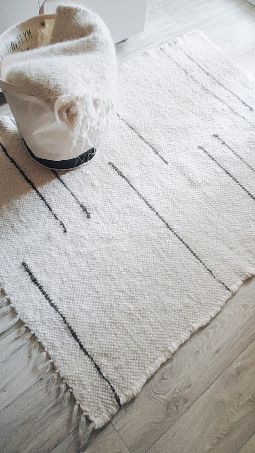 Natural undyed wool rug, ivory base with dark gray stripe pattern, handwoven using traditional techniques