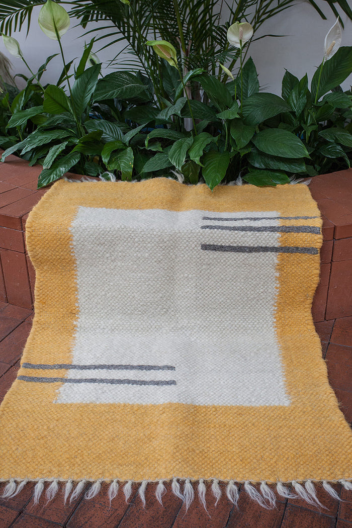 Olava rug — minimalist wool rug with ivory base, bold orange edge framing, and delicate hand-sewn dark gray stripes
