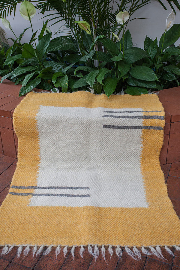 Olava rug — minimalist wool rug with ivory base, bold orange edge framing, and delicate hand-sewn dark gray stripes