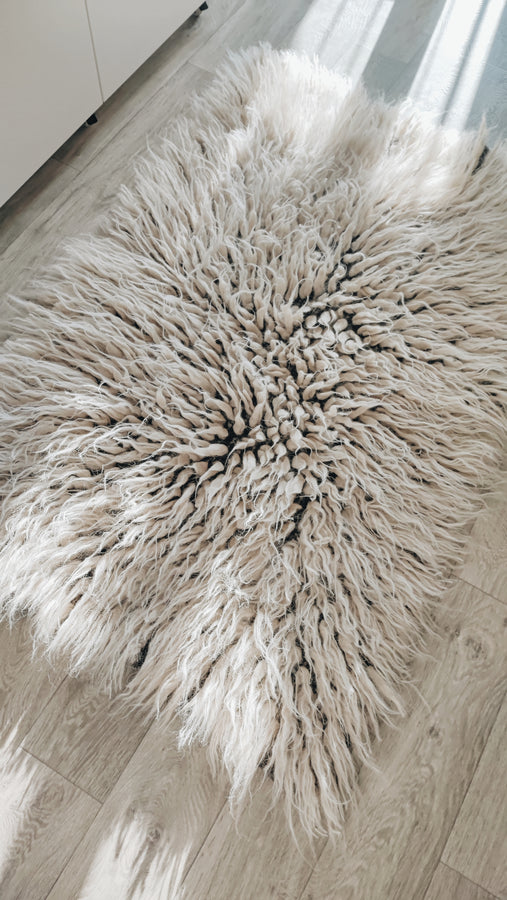 Hand-knotted flokati wool rug, soft deep-pile texture in light gray, natural undyed sheep wool craftsmanship