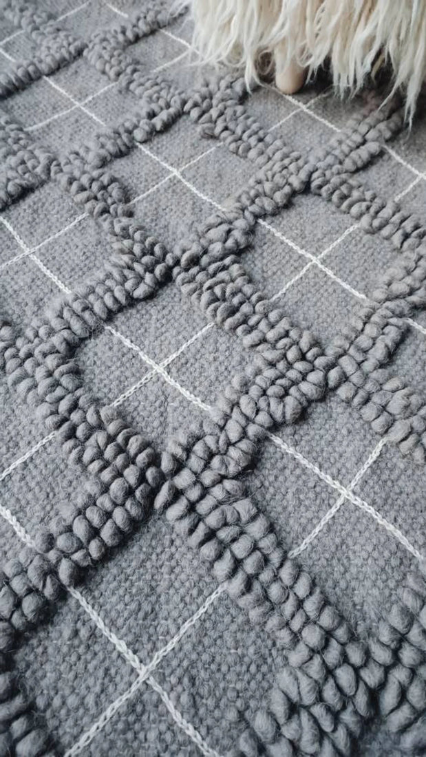 Natural wool rug, all-gray diamond motif with tactile looped texture, accented by artisan hand-embroidered geometric details