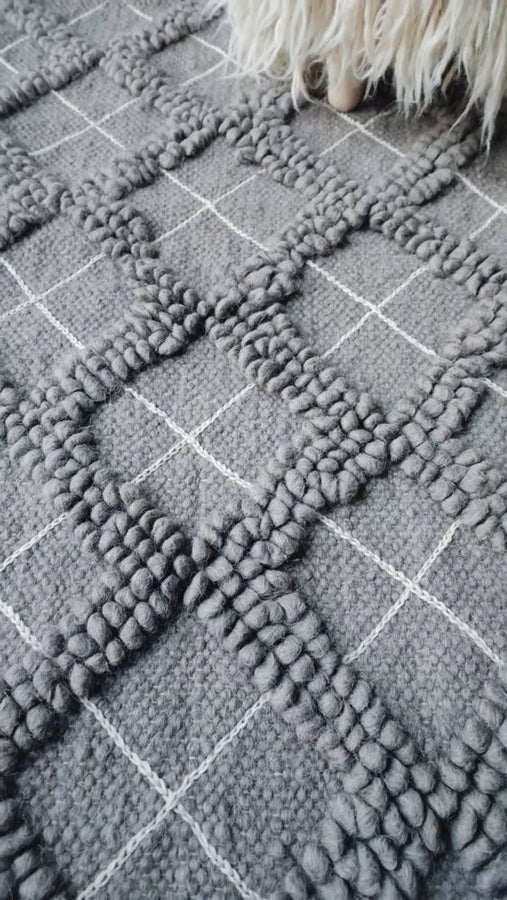 Natural wool rug, all-gray diamond motif with tactile looped texture, accented by artisan hand-embroidered geometric details