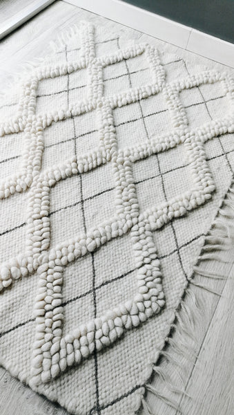 Sula rug — handwoven ivory white wool rug with sculptural diamond bobble texture and contrasting hand-embroidered diamond accents
