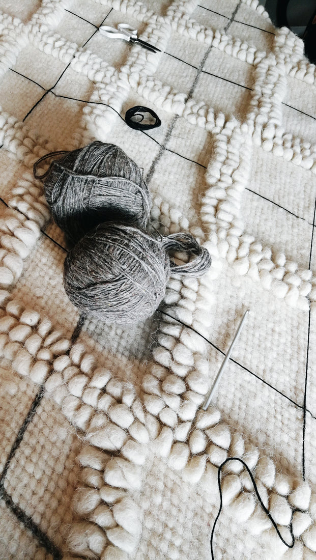 Three-dimensional ivory wool rug with textured diamond geometry and contrasting hand-embroidered diamond outlines, a refined statement piece