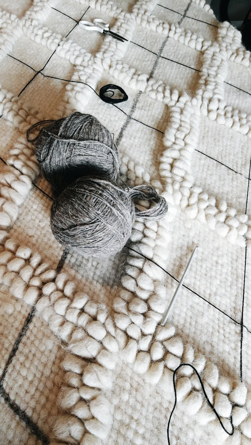 Three-dimensional ivory wool rug with textured diamond geometry and contrasting hand-embroidered diamond outlines, a refined statement piece