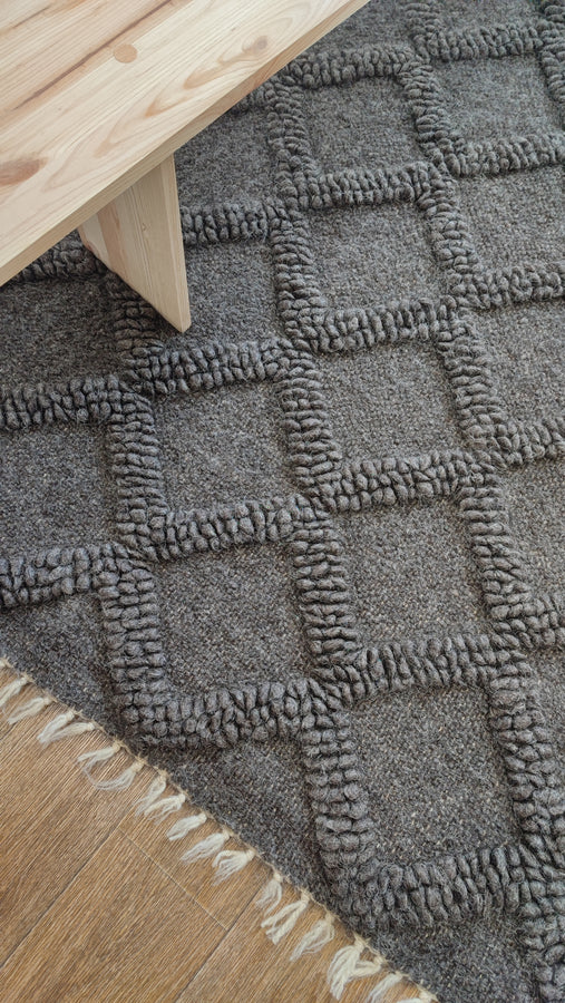 Natural undyed wool rug featuring subtle bobble-woven diamonds in matching tone, dark gray colorway, handcrafted using traditional techniques