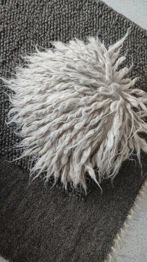 Artisanal wool pillow styled in minimalist living room on dark gray Mapico rug
