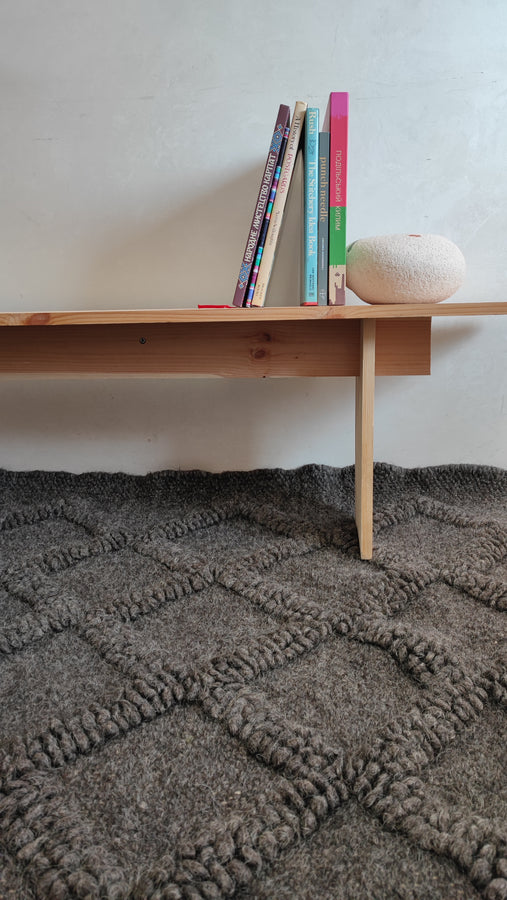 Contemporary minimalist wool rug with subtle diamond relief texture in matching wool tone, natural undyed sheep wool craftsmanship