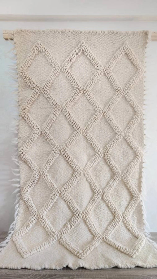 Three-dimensional ivory wool rug, diamond pattern with tactile bobble texture, an artisan-made design icon
