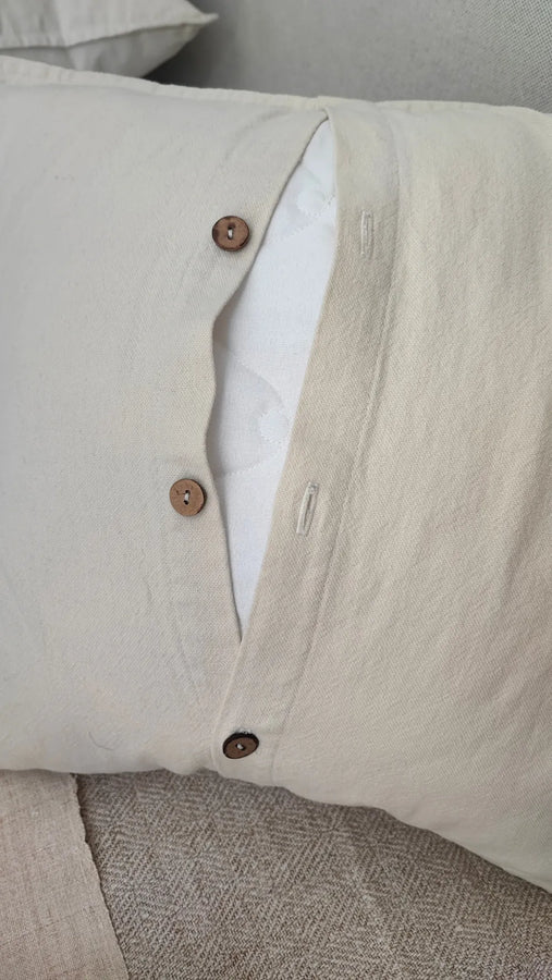 Detail of Mapico pillow's natural wooden button closure and linen-cotton fabric texture