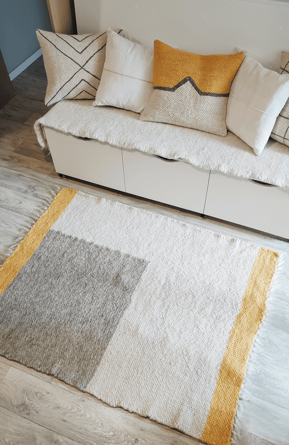 Handmade organic wool rug showcasing a blend of natural ivory white, grey, and orange yarn