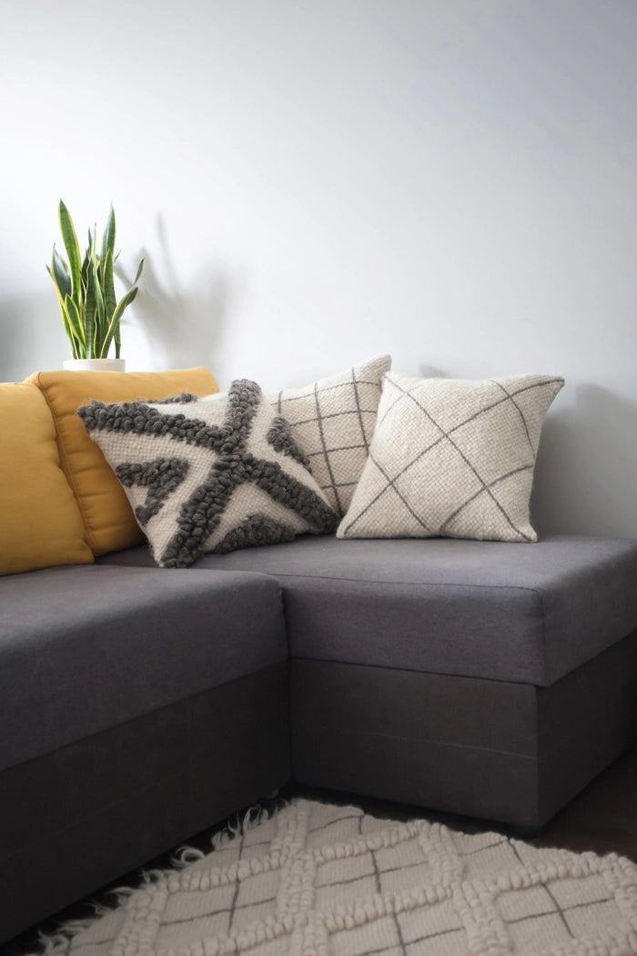 Handmade wool Chaga pillow styled on a living room sofa with MAPICO rug on the floor