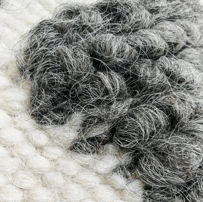 Close-up of textured wool bobbles forming Chaga pattern on handmade pillow