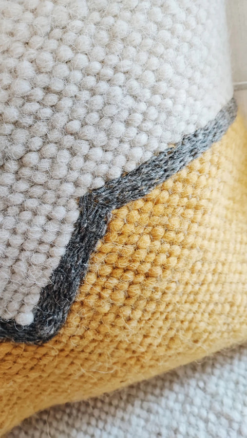 Close-up of hand-embroidered gray detail on Olava orange wool cushion