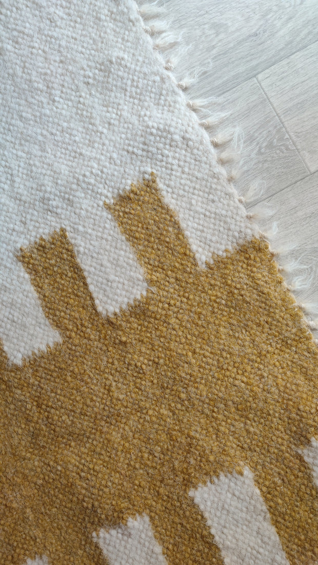 Murafa rug — minimalist wool rug with vertical Aztec-style geometric band, available in ivory-orange