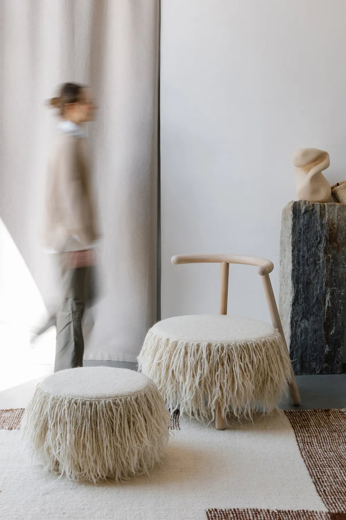 Set of wool accent chair and Mapico pouf in a modern interior near a woman