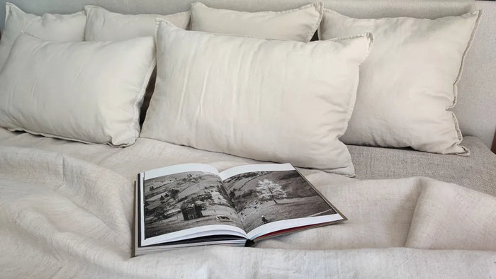 Set of Mapico premium linen cushions layered on a bed in a serene, neutral bedroom interior