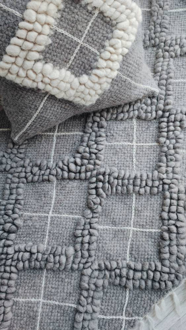 Three-dimensional gray wool rug with textured diamond geometry and contrasting hand-embroidered diamond white outlines, a refined statement piece