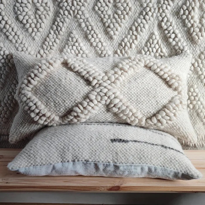 Close-up of white wool cushion with hand-woven geometric texture