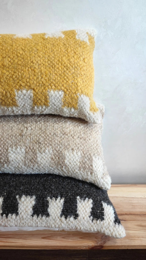 Three Murafa wool lumbar pillows in beige, orange, and black colorways