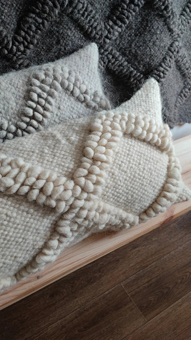 Two Tern wool pillows in white and gray on a bench