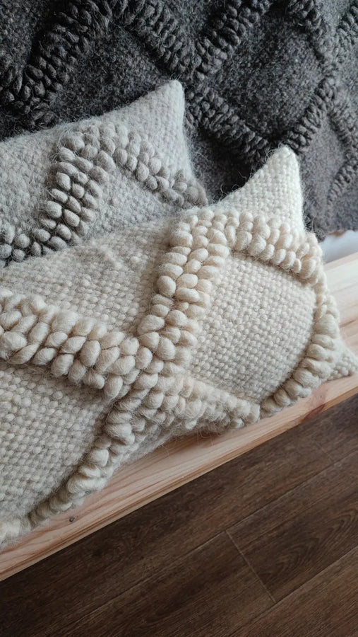 Two Tern wool pillows in white and gray on a bench