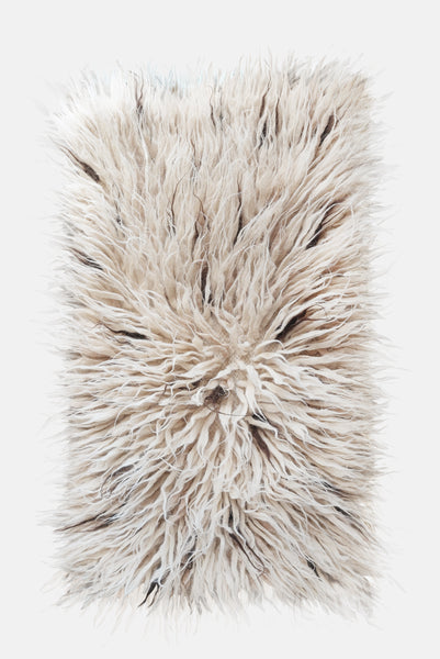 Flokati wool rug in ivory white with scattered beige and brown accent strands, deep-pile natural texture
