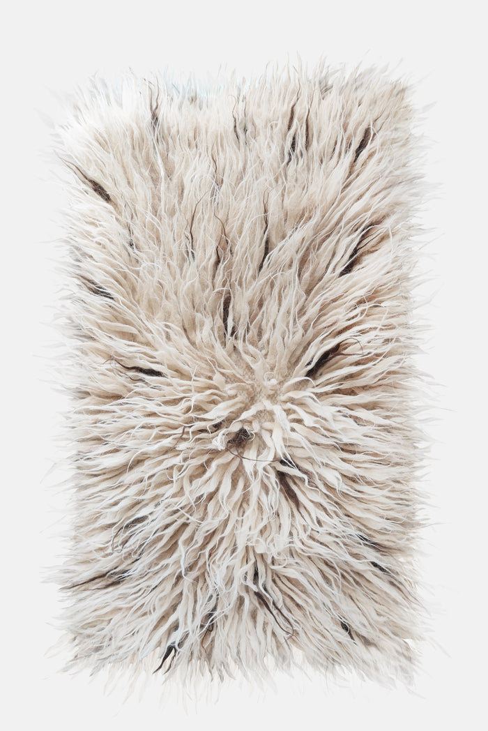 Flokati wool rug in ivory white with scattered beige and brown accent strands, deep-pile natural texture