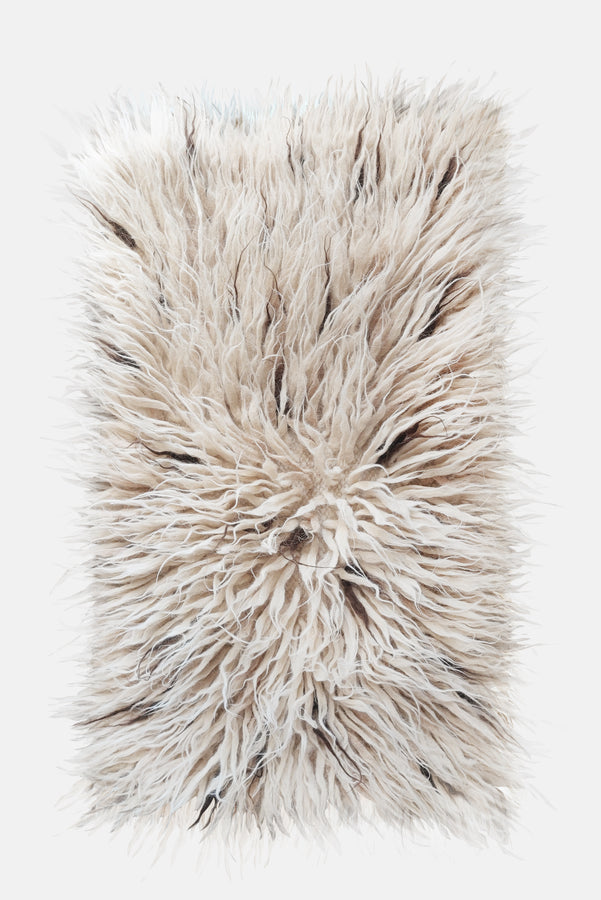 Flokati wool rug in ivory white with scattered beige and brown accent strands, deep-pile natural texture